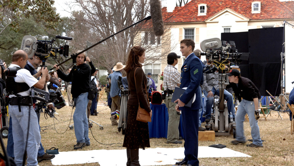 Ashton Kutcher in a military uniform while surrounded by cameras while filming for a movie.